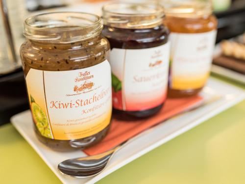 four jars of jam on a tray with a fork at viavelo hotel am Seepark in Freiburg im Breisgau