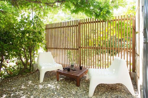 2 chaises blanches et une table basse en face d'une clôture dans l'établissement GregBnb - Studio CLIMATISÉ - Terrasse & parking privé, à Toulon