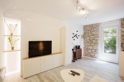 un salon avec une télévision sur un mur blanc dans l'établissement GregBnb - Studio CLIMATISÉ - Terrasse & parking privé, à Toulon