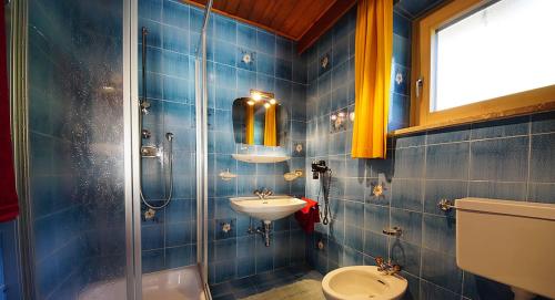a blue tiled bathroom with a sink and a toilet at Lüch da Spescia in La Valle