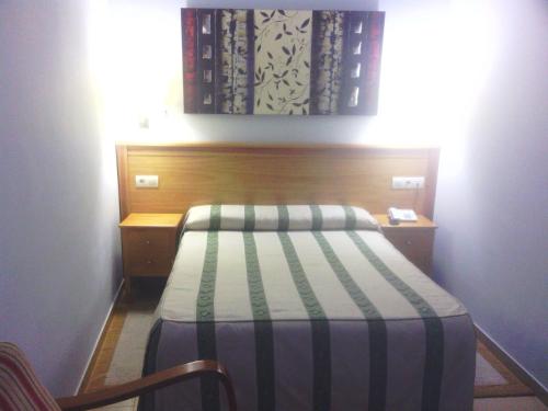 a small bedroom with a bed and a wooden headboard at Hotel Goya in Seville