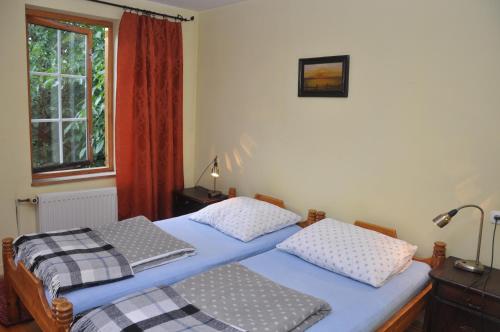 two twin beds in a bedroom with a window at Dom Gościnny in Gietrzwałd