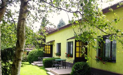 a green house with a table and chairs in the yard at Wilcza Chata in Kołczewo