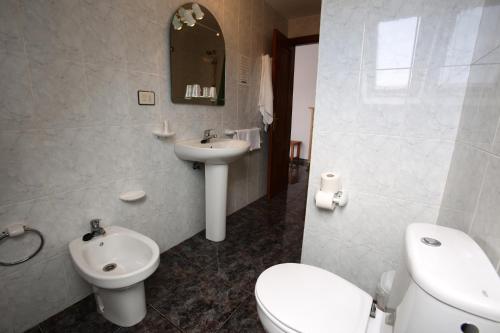 a bathroom with a white toilet and a sink at Hostal San Roque in Portonovo