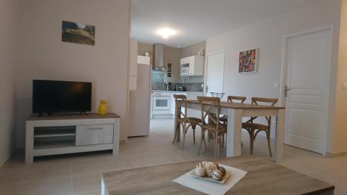 een keuken en een woonkamer met een tafel en een televisie bij LES LAUZES DE ST MICHEL-LA SARRIETTE in Entrechaux