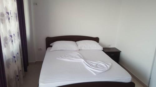 a bed with white sheets and pillows in a bedroom at Grand Seaview Apartments in Ksamil