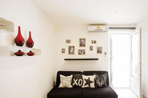 ein Wohnzimmer mit einem schwarzen Sofa und roten Vasen in der Unterkunft GregBnb-com - Studio Cosy - CLIMATISÉ - WIFI - 15min Gare in Toulon