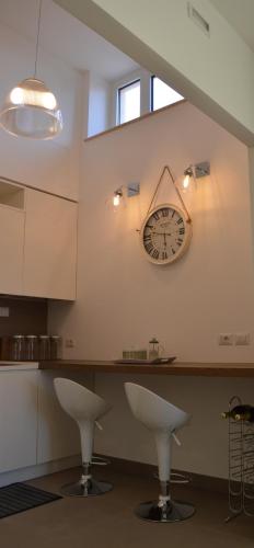 a clock on the wall of a kitchen with two stools at Maison Margot in Acquaviva Picena