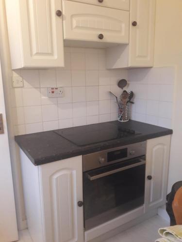 a kitchen with white cabinets and a black counter top at Brick Kiln Apartment in Campsea Ashe