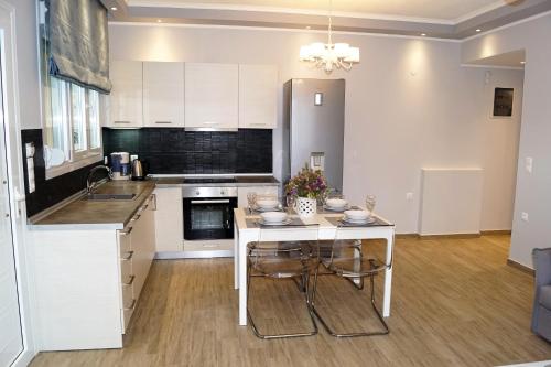 a kitchen with white cabinets and a table with chairs at Melody Apartments in Agios Nikolaos