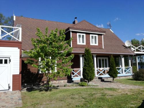 a brown house with a white garage at Lakeshore house in Dvarčėnai