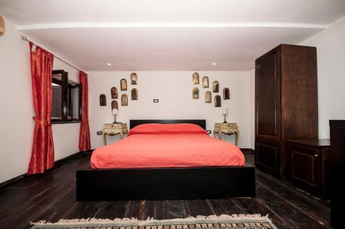 B&B La Mimosa في San Pietro: غرفة نوم بسرير احمر وطاولتين جانبيتين