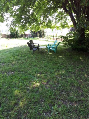 three park benches sitting in the grass under a tree at Villa SAINT-PRIVAT in Pouzilhac