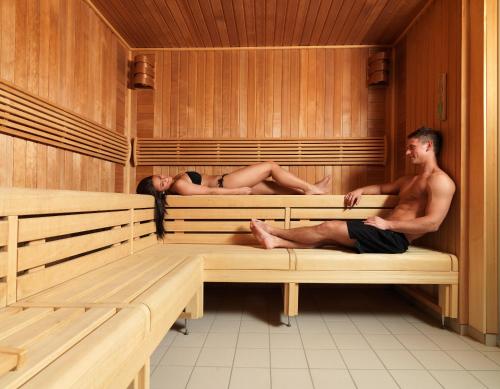 two people sitting on benches in a sauna at Strand Hotel Fevik - by Classic Norway Hotels in Fevik