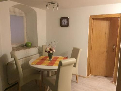 a dining room with a table and chairs and a clock at Springer-Apartment-1215 in Kurort Oberwiesenthal