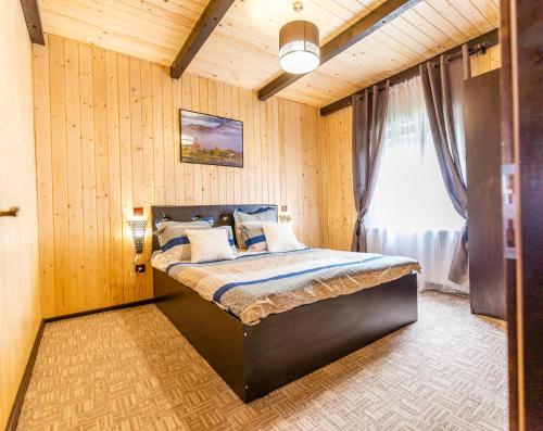 - une chambre avec un lit dans une pièce dotée de murs en bois dans l'établissement Licurici, à Colibiţa