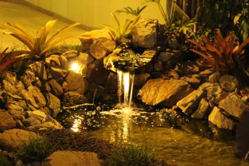 a water fountain in a garden with rocks at Café Palace Hotel in Três Pontas
