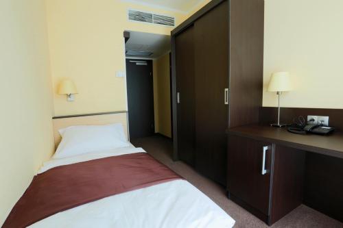 a hotel room with a bed and a desk and cabinets at Casino & Hotel ADMIRAL Ptuj in Ptuj