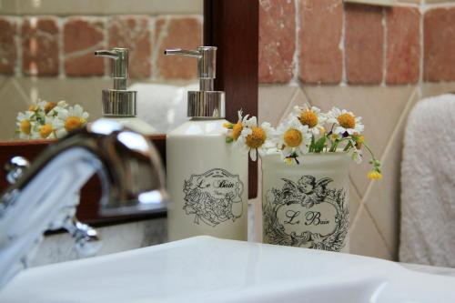 two white bottles of soap and flowers on a sink at B&B Locanda dei Tigli in Serravalle dʼAsti