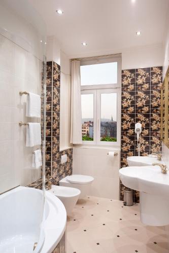 a bathroom with two toilets and two sinks and a window at Green Garden Hotel in Prague