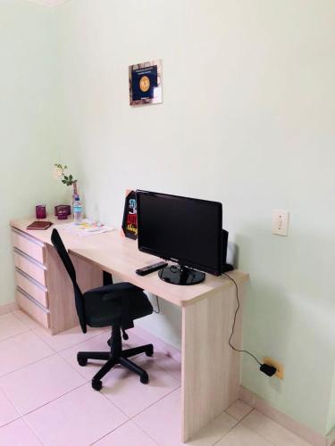 a desk with a computer monitor and a chair at Hospedagem Granville in Sao Paulo