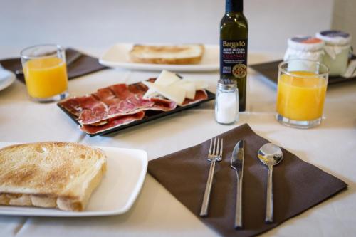 a table with a plate of bread and toast and orange juice at HostalTina in Bossost