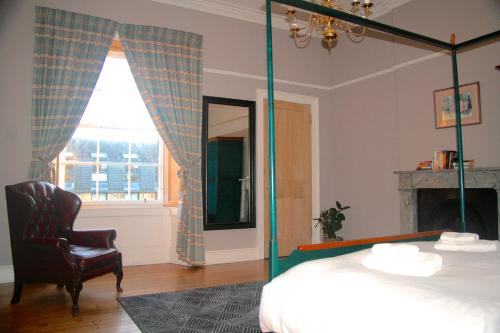 a bedroom with a bed and a chair and a mirror at Hopetoun Grande Georgian Apartment in Edinburgh