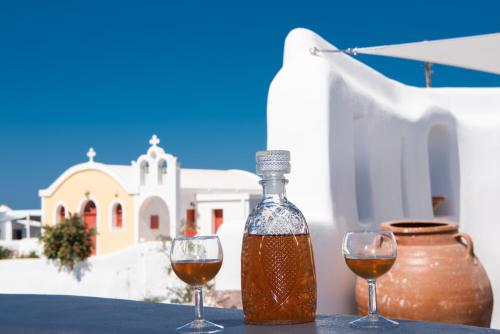 two glasses of wine on a table in front of a building at Caves 1880 in Oia