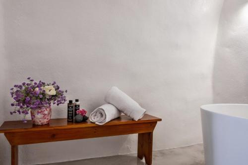 a wooden table with towels and a vase of flowers at Abelis Canava Luxury Suites in Vóthon