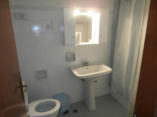 a white bathroom with a sink and a toilet at Hotel Aris in Methoni