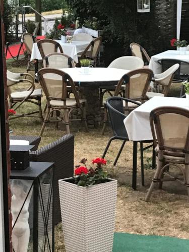 a group of tables and chairs with red flowers in a vase at Elbhotel Bleckede am Hafen in Bleckede