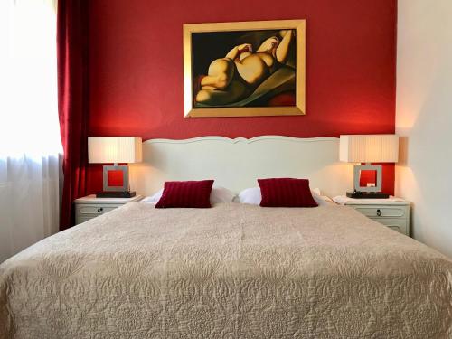 a bedroom with a bed with red walls and two lamps at Hotel Wenus in Kazimierz Dolny