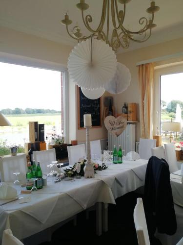 a dining room with a table with white chairs and a chandelier at Elbhotel Bleckede am Hafen in Bleckede