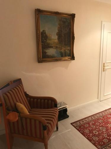 a living room with a chair and a painting on the wall at Elbhotel Bleckede am Hafen in Bleckede