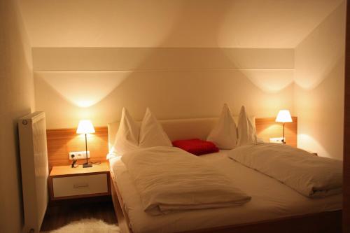 a bedroom with a large white bed with two lamps at Pension Café Maier in Golling an der Salzach