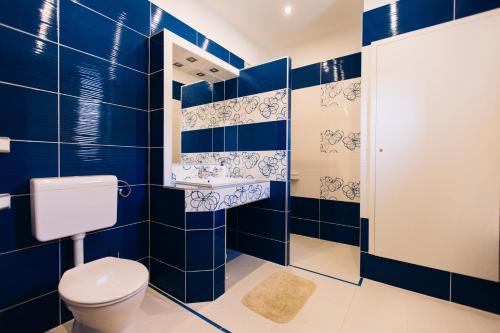 a blue tiled bathroom with a toilet and a shower at Lak6 Apartment in Mórahalom
