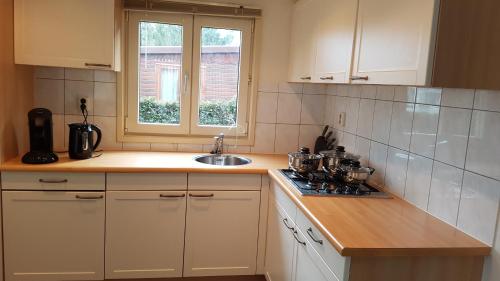 a kitchen with white cabinets and a sink and a window at Deluxe Holiday Home in Putten