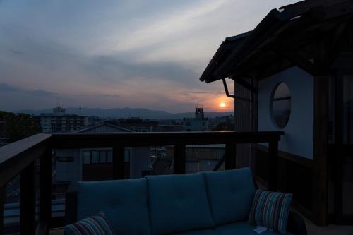 a couch on a balcony with the sunset in the background at Terrace Kiyomizu Kyoto in Kyoto
