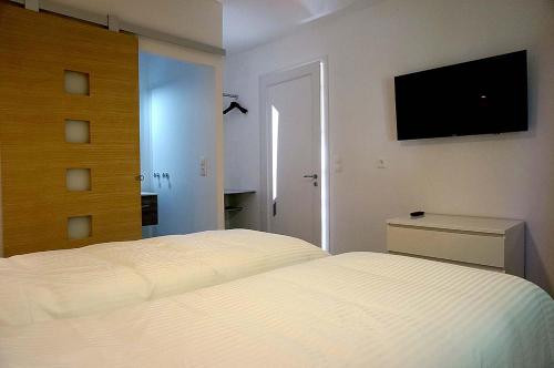a bedroom with a white bed and a flat screen tv at Villa hortensia in Carpentras