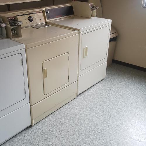 an empty laundry room with white washers and dryers at Keystone Hotel in Valdez