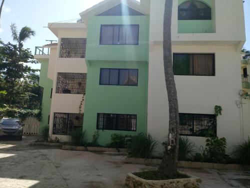 a building with a palm tree in front of it at Riviera Punta Cana Eco Travelers in Punta Cana