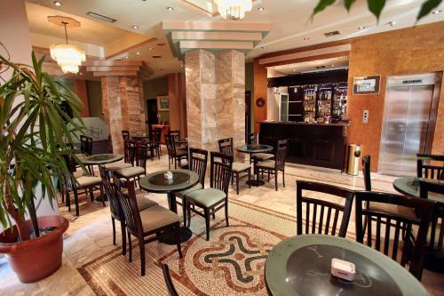 un restaurante con mesas y sillas y un bar en Hotel Regency, en Korçë