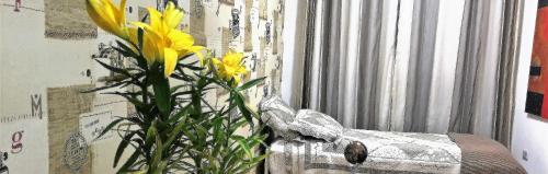 żółty kwiat w wazie obok okna w obiekcie Mello's House w mieście Kurytyba