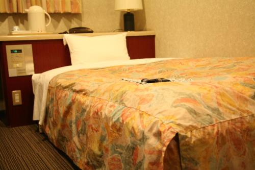 a hotel room with a large bed with a colorful blanket at Hotel Ikeda in Nagasaki