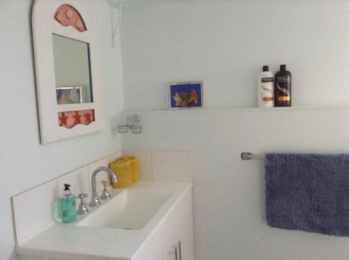 een witte badkamer met een wastafel en een spiegel bij Studio Apartment with Seaview in Airlie Beach