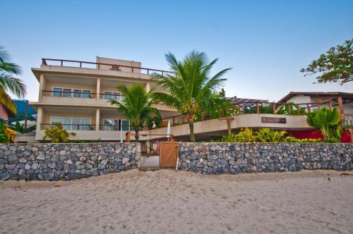 a building on the beach next to a fence at Juquehy La Plage Hotel in Juquei