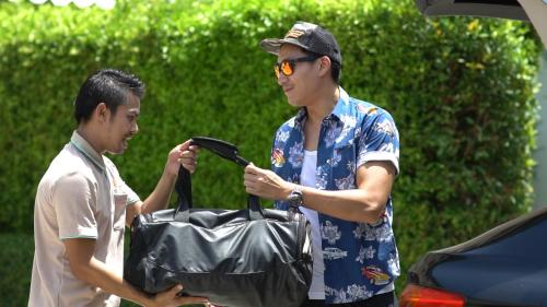 two men standing next to a car with a bag at Talay Hotel and Villa Cha-am in Cha Am
