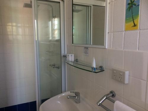 a bathroom with a shower and a sink and a mirror at Tropical Palms Resort & 4WD Hire in Picnic Bay