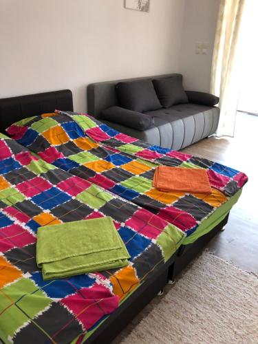 a bed with a colorful quilt on it with a couch at Zamárdi Parti Apartman in Zamárdi