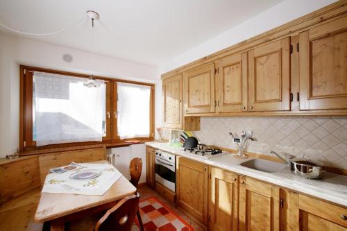 a kitchen with wooden cabinets and a sink and a table at Appartamenti da Nica e Diego in Borca di Cadore
